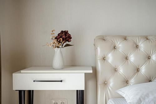 a white table with a vase of flowers on it next to a bed at The Central Collection Apartments in Chişinău