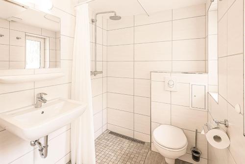 a white bathroom with a toilet and a sink at Bungis - 28 Ferienhäuser Am Grimnitzsee G3 in Joachimsthal