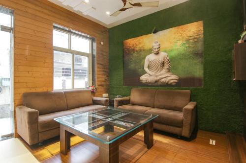 a living room with two couches and a painting of a guru at Hotel Rosewood Inn in Amritsar