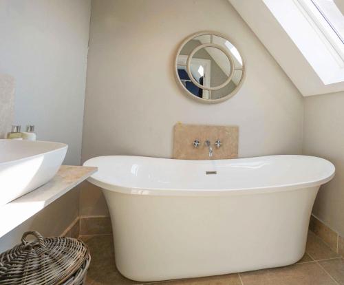 une baignoire blanche dans une salle de bain avec un lavabo dans l'établissement Peaceful Rural Cottage with hot tub, à Fenton
