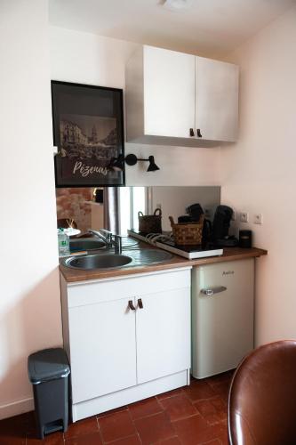 une cuisine avec des armoires blanches et un évier dans l'établissement Studio Marcette, Centre Historique - Wifi, à Pézenas