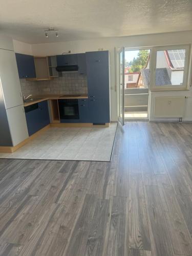 an empty kitchen with blue cabinets and a wooden floor at Ferienwohnung in Geislingen an der Steige