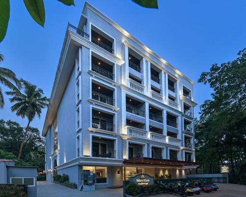 a tall white building with a restaurant in front of it at Meritas Auberge Calangute Goa in Calangute