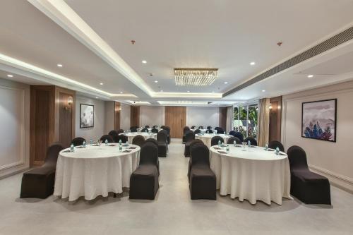 a conference room with tables and chairs and a chandelier at Meritas Auberge Calangute Goa in Calangute