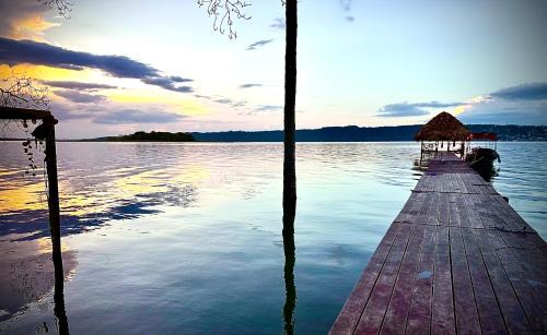a dock on a body of water with the sun setting at Villa Tayasal in Flores