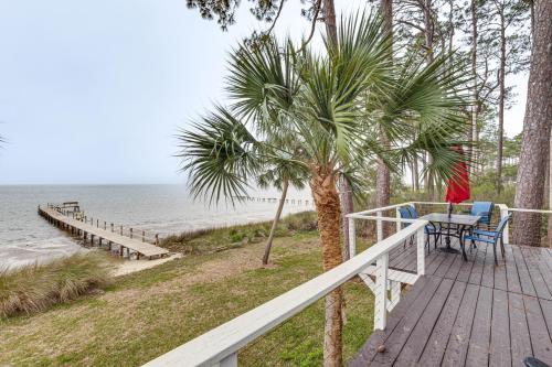 a wooden deck with a table and chairs next to the beach at Carrabelle Retreat with Boat Dock and Views of Gulf! in Carrabelle