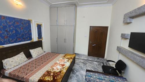 a small bedroom with a bed and a tv at Darul Khair in Lahore