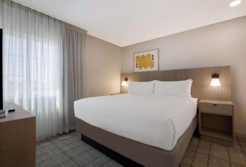 a bedroom with a large white bed and a window at Sonesta Simply Suites Baltimore BWI Airport in Linthicum Heights
