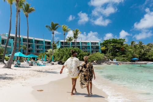 a man and woman walking on the beach at Secret Harbour Beach Resort in St Thomas