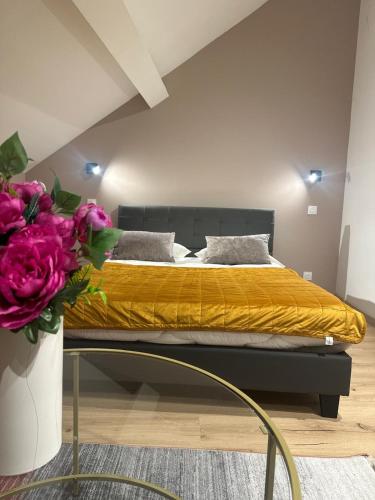 a bedroom with a bed and a vase of flowers at Gîtes by Hôtel Les Reflets Jaunes in Givet