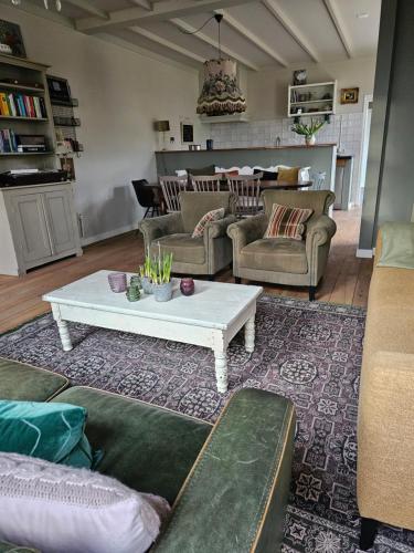 a living room with couches and a coffee table at Logeerderij tussen Koe & Kroonluchter in Diessen