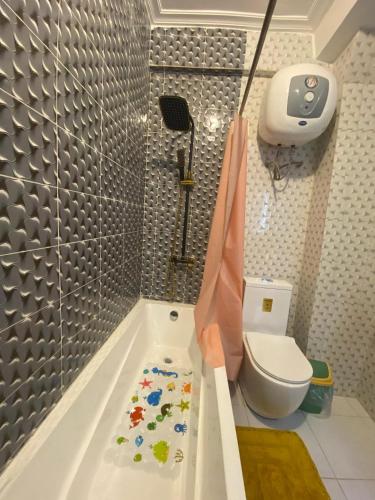a bathroom with a bath tub and a toilet at Résidence hôtelière MEDOM Palace, Bastos in Yaoundé