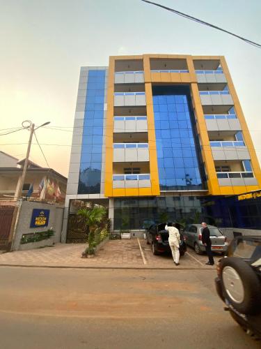 a tall building with people walking in front of it at Résidence hôtelière MEDOM Palace, Bastos in Yaoundé