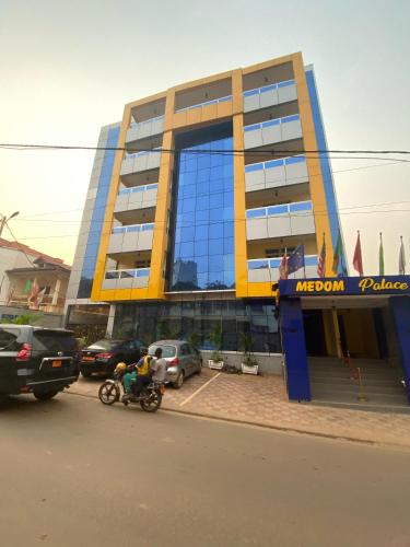 a building with a motorcycle parked in front of it at Résidence hôtelière MEDOM Palace, Bastos in Yaoundé