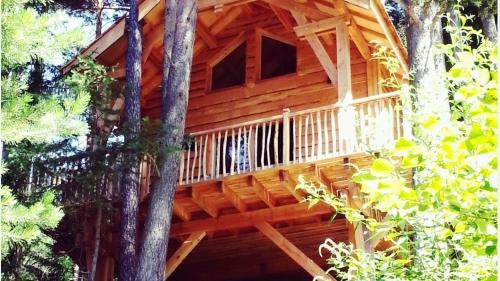 une cabane en rondins avec un balcon dans les arbres dans l'établissement Cabanes des Pins Sylvestres Boréon, à Saint-Martin-Vésubie