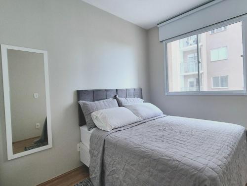 a bedroom with a bed with a mirror and a window at Laguna 1212 - Moderno e Funcional in Sao Paulo