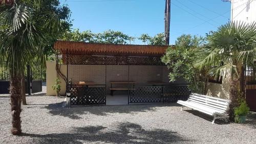 a pavilion with a bench in a park with palm trees at Nika house in Ureki