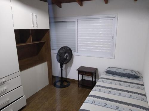 a room with two beds and a fan and a window at Casa em Boiçucanga in São Sebastião