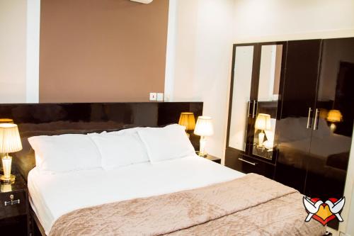 a bedroom with a large white bed and two lamps at Whispering Hearts Guest House in Bortianor