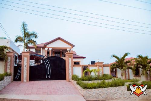 a house with a large gate in front of it at Whispering Hearts Guest House in Bortianor