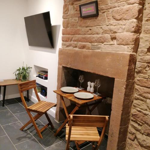 a dining room with a table and chairs and a stone fireplace at The Burrow in Penrith