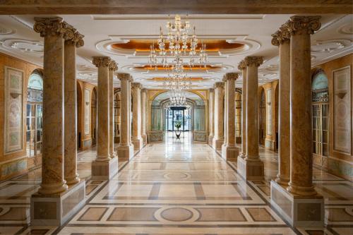 an ornate hallway with columns and a chandelier at InterContinental Athenee Palace Bucharest by IHG in Bucharest