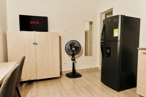 a kitchen with a black refrigerator and a fan at Apartahotel Poblado-Aguacatala in Envigado