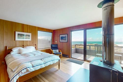 a bedroom with a large bed and a large window at Rolling Waves Beach House in Sea Ranch