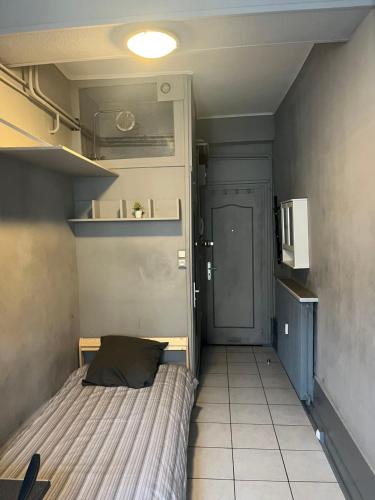 Cette petite chambre comprend un lit et une porte. dans l'établissement Studio au cœur de Dijon, à Dijon