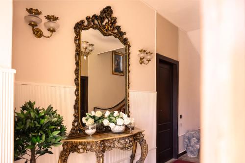 a mirror on a wall next to a table with flowers at B&B L'EDEN in Cassino