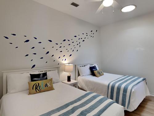 a bedroom with two beds and a wall with a fish decal at Calle Bonita Townhomes #1714 in Pensacola Beach