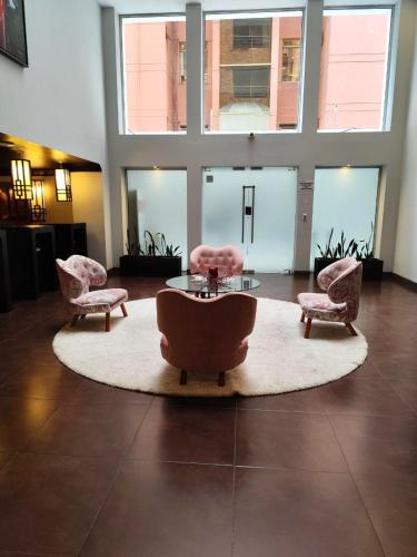 a living room with chairs and a table and a large window at Penthouse lujo, Parque La Carolina, Piscina, parqueo 3 habitaciones in Quito