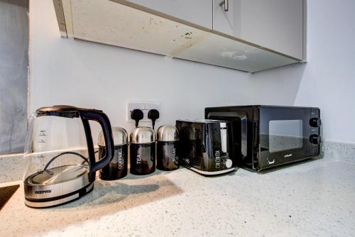 a kitchen counter with a toaster and a microwave at 1 BR Flat 6 Mins From Heathrow Airport Flat 25 in Harmondsworth