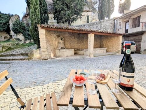 - une bouteille de vin et un bol de fruits sur une table de pique-nique dans l'établissement Le Joannis - Tranquillité en centre historique, à Malaucène