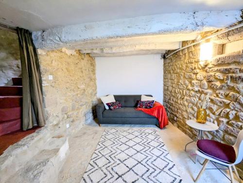 un salon avec un canapé et un mur en pierre dans l'établissement Le Joannis - Tranquillité en centre historique, à Malaucène
