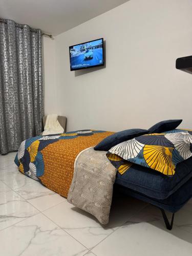 une chambre avec un lit et une télévision au mur dans l'établissement Quiet apartment near metro, à Pantin