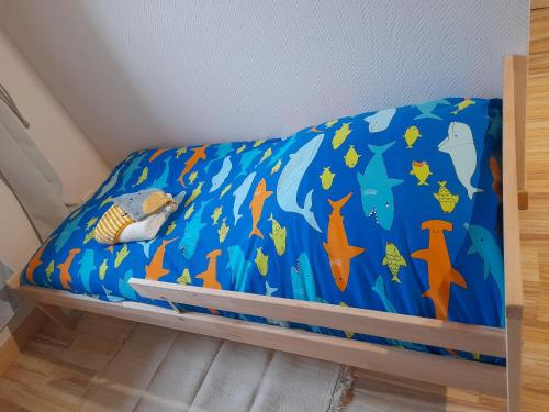 a bed with a blue sheet with fish and stars at Domaine de la Tour carrée - 3 Chambres in Benoîtville