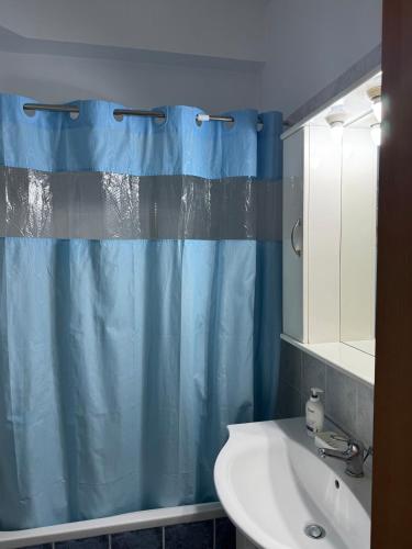 a bathroom with a blue shower curtain and a sink at Apartment in Komotini in Komotini