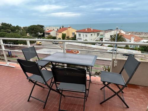 una mesa y sillas en un balcón con vistas a la calle en Appartement « pépite » vue mer, en Saint-Cyprien
