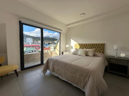 a bedroom with a large bed and a large window at Wow! Ushuaia Apartments in Ushuaia