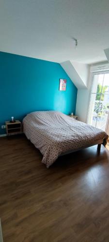 une chambre avec un lit avec un mur bleu dans l'établissement Chez Irène & Alan - Maison Pila, à La Fresnais