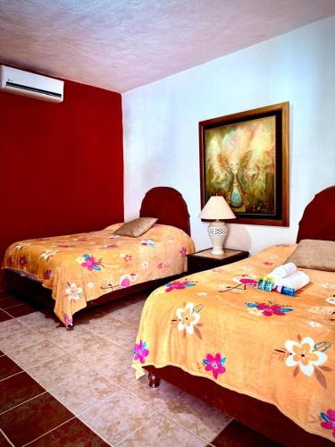 a bedroom with two beds and a painting on the wall at La Casita Inn Bustamante in Bustamante
