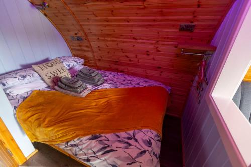 a small bed in a room with a wooden wall at Fulshaw Mill Holidays in Stewarton