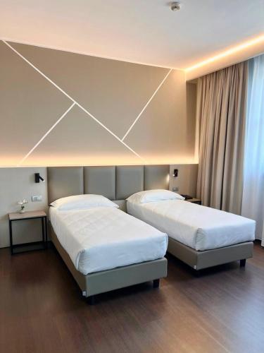 two beds in a hotel room with two beds sidx sidx sidx at Unico Hotel in Ossona