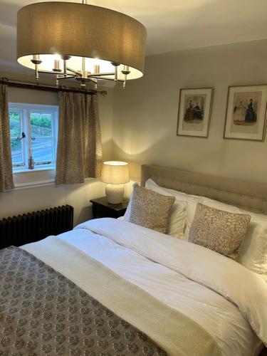 Schlafzimmer mit einem weißen Bett und einem Kronleuchter in der Unterkunft Mantlemas Cottage in Turners Hill
