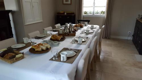 une grande table avec des nappes blanches et de la vaisselle dans l'établissement Maison Le Mans chambre parentale, au Mans
