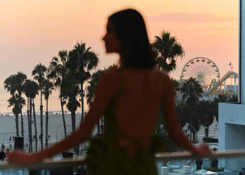 a woman walking in front of a ferris wheel at Regent Santa Monica Beach in Los Angeles