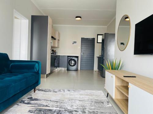 un salon avec un canapé bleu et une cuisine dans l'établissement Mikeys place On New: 2bed2bath no.1 with Free WiFiNetflix, à Midrand