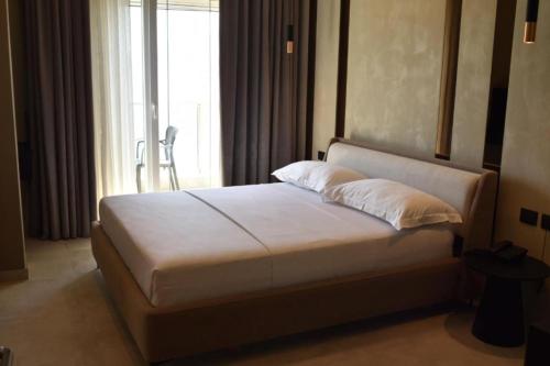 a bedroom with a white bed with a window at Nuna Hotel & Apartments in Vlorë