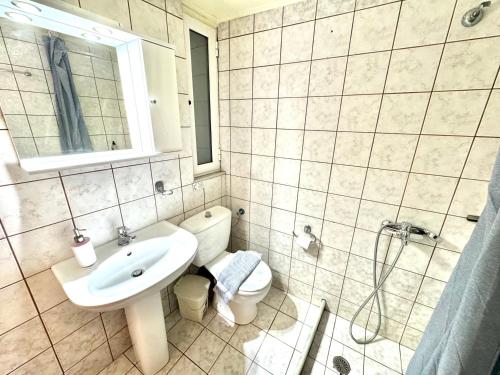 a white bathroom with a sink and a toilet at George Airport Apartments in Heraklio